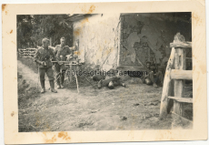 Soldaten der Wehrmacht mit Maschinengewehr MG 34 neben einem toten Soldaten